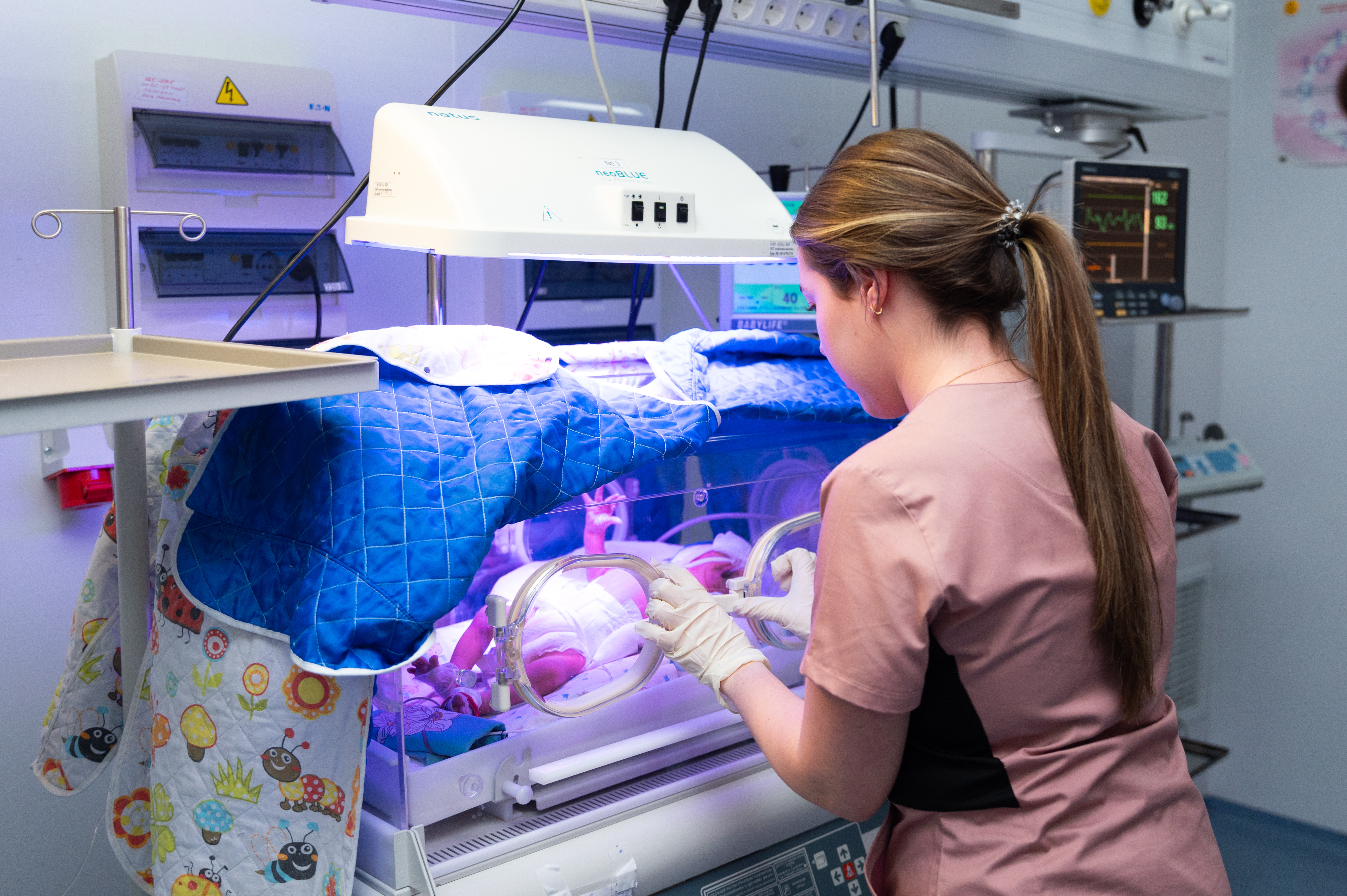 A nurse cares for a newborn in an incubator