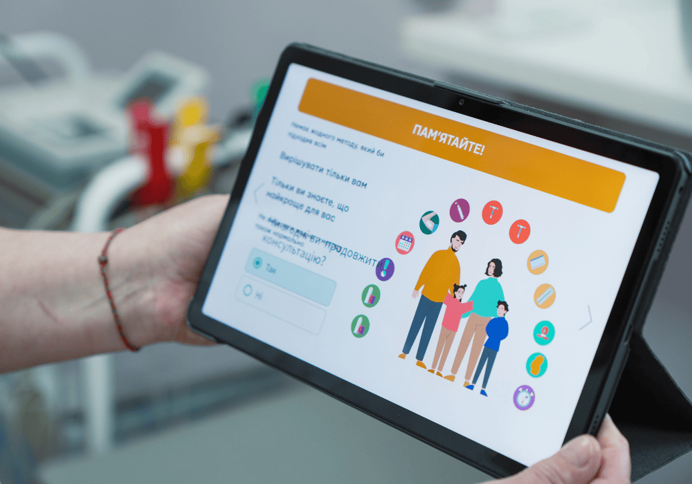 Zoom-in on the tablet application showing family planning services available, illustrated with clipart images of a family surrounded by icons representing different services