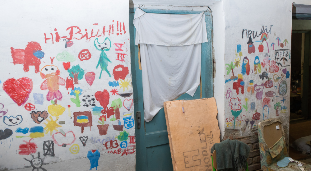 Colourful children's drawings on a white wall surrounding a wooden mint-coloured door