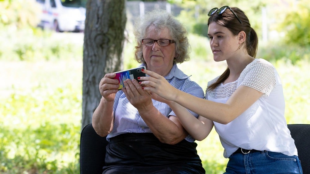 Volunteer Catalina Neghina shows her former teacher Elena Gobjila how to get online using her mobile phone.