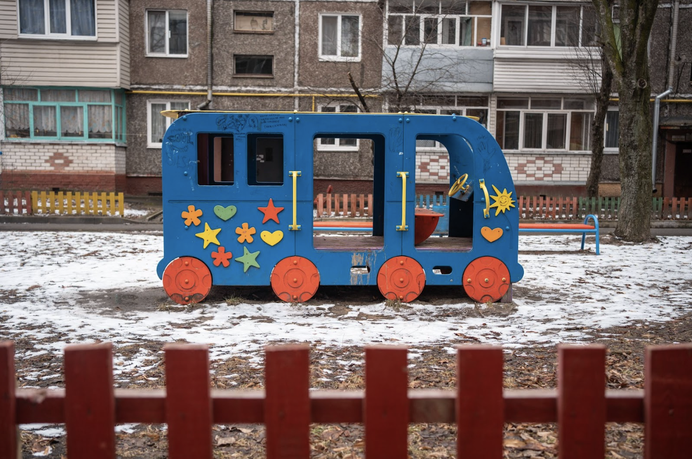 A colorful play bus sits outside, surrounded by snow.