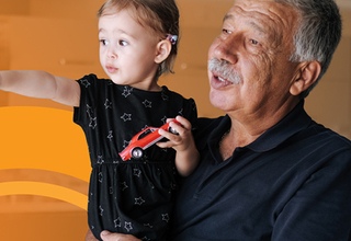 An older man holding a young child who is pointing into the distance.