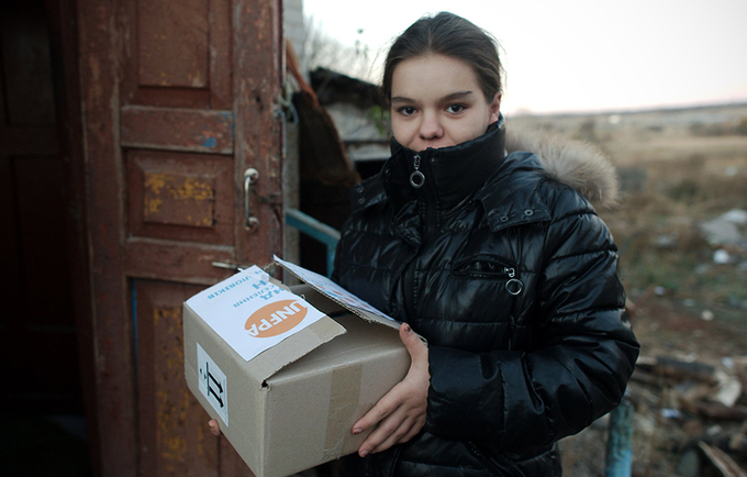 A young woman stands holding a UNFPA box