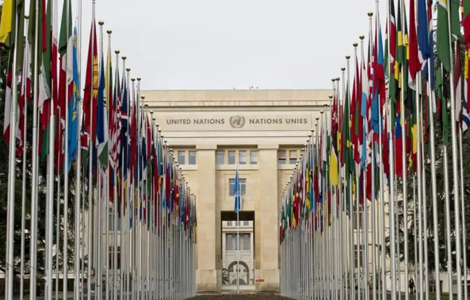 Photograph of the exterior of the United Nations building in Geneva with two rows of flags.