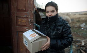 A young woman stands holding a UNFPA box