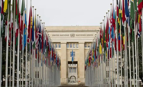 Photograph of the exterior of the United Nations building in Geneva with two rows of flags.