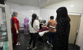 Group of health care workers in a hospital room gather around to observe a woman having an ultrasound