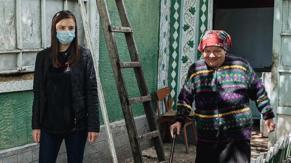 A young woman and an older woman walk together outside