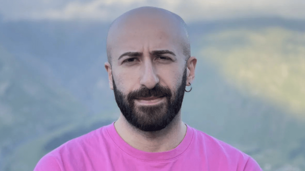 Close up photo of Beka Gabadadze, with dark beard and pink shirt