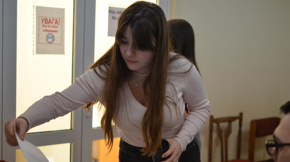 A woman bends over picking up some papers