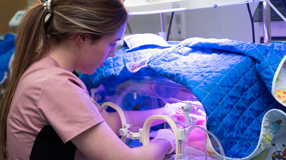 A nurse cares for a baby in an incubator