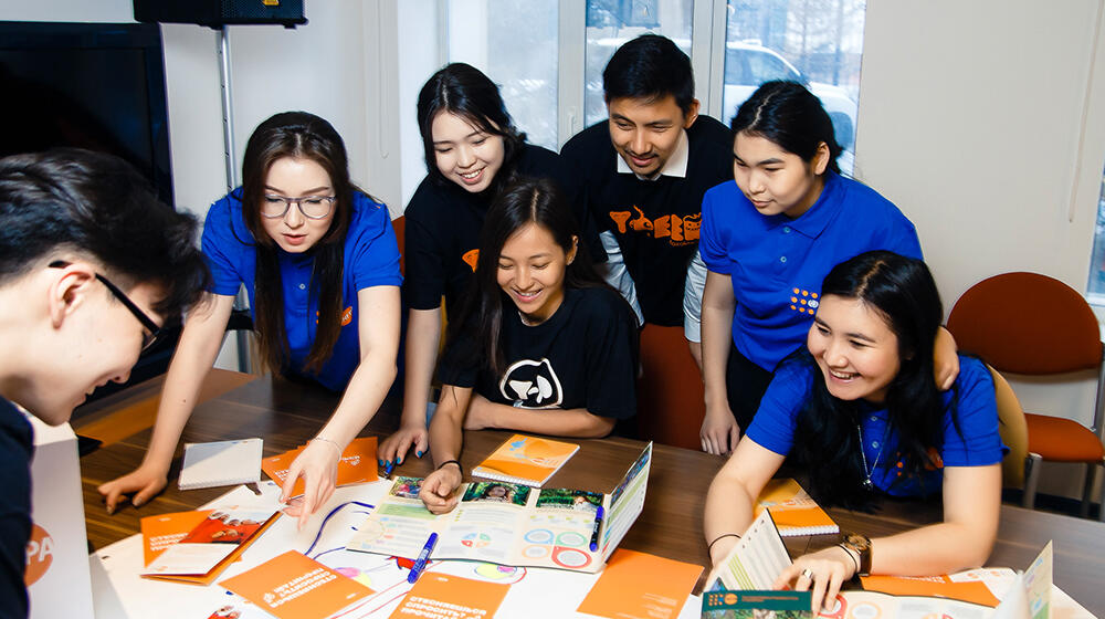 A group of young people look at papers together.