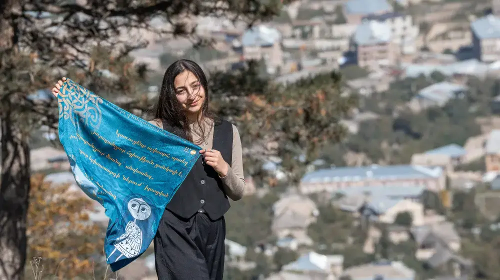 Neli Nersisyan, holding a blue scarf featuring the image of NE