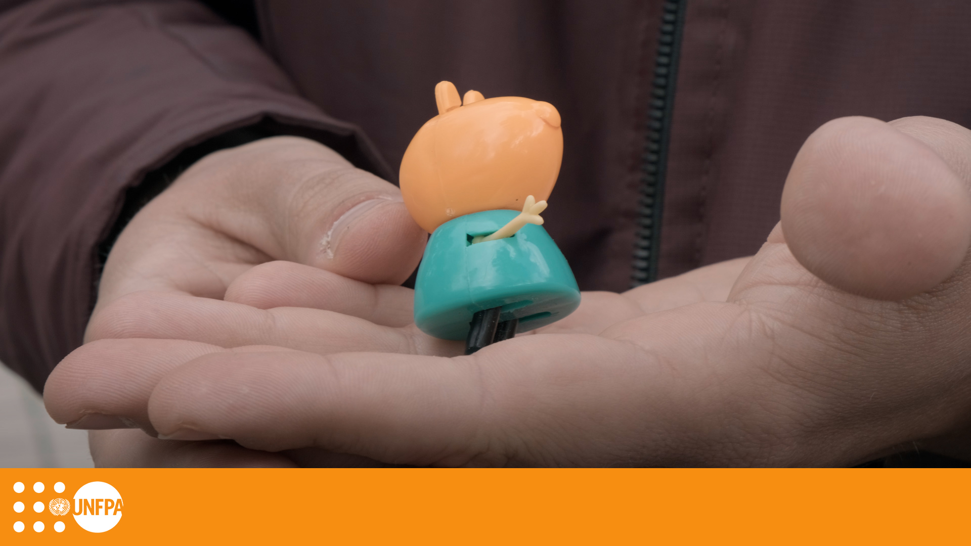 A close-up shot of a pair of hands holding an orange and teal children's toy